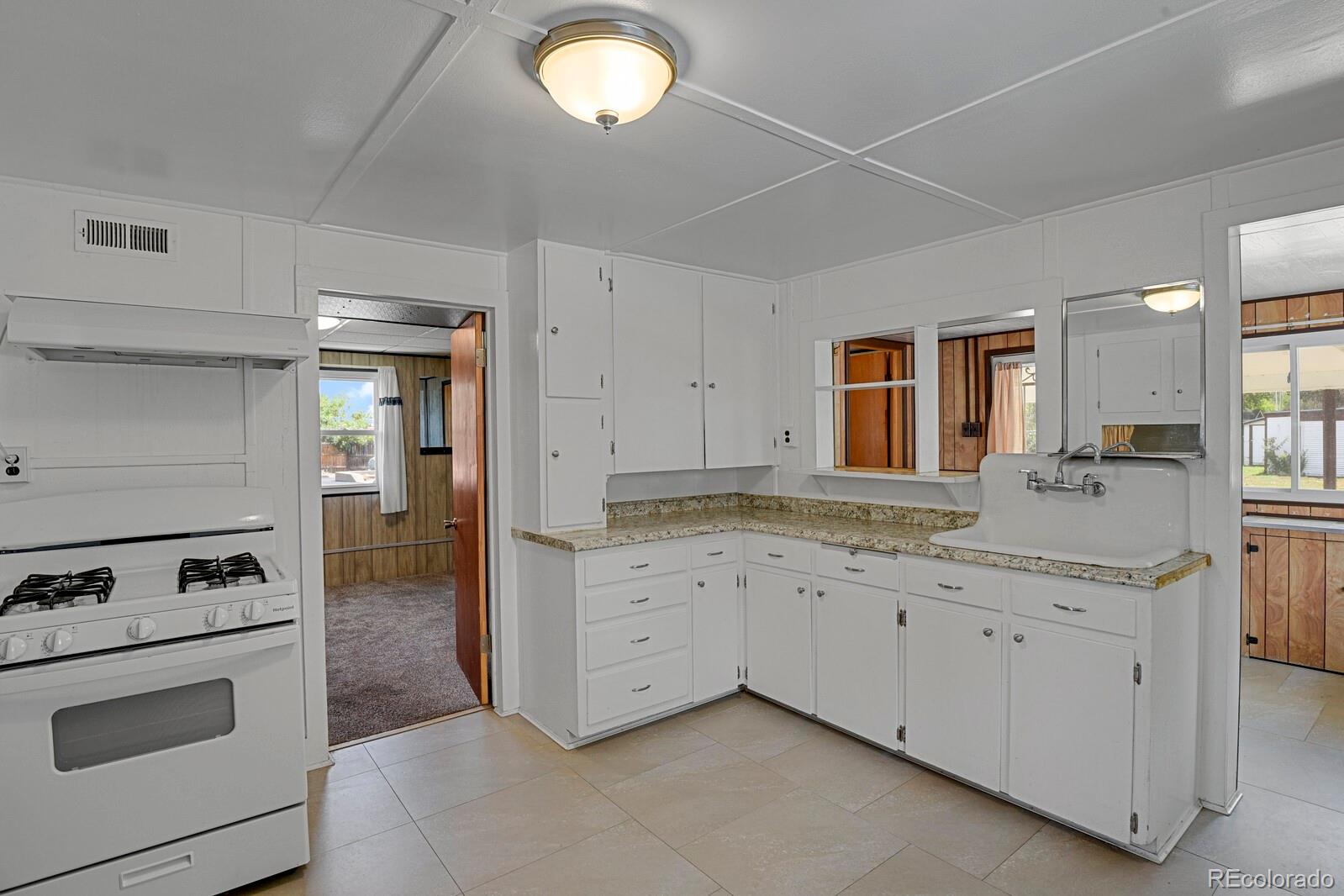 12400 West 44th Avenue Wheat Ridge, CO 80033 - Photo 12 of 31 a kitchen with granite countertop white cabinets and white appliances