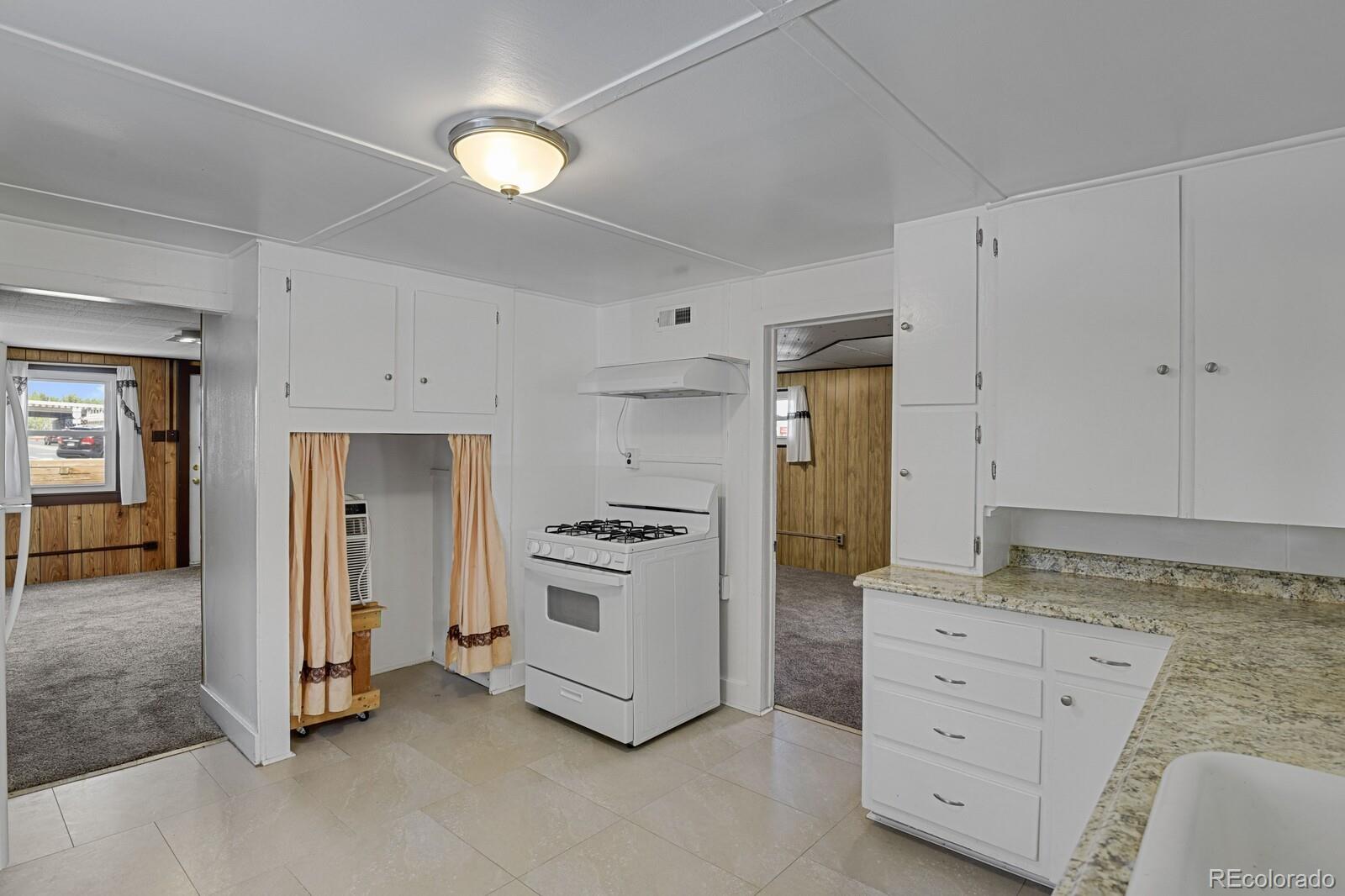 12400 West 44th Avenue Wheat Ridge, CO 80033 - Photo 13 of 31 a kitchen with white cabinets and stainless steel appliances
