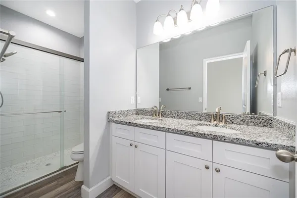 a bathroom with a granite countertop sink a mirror and shower