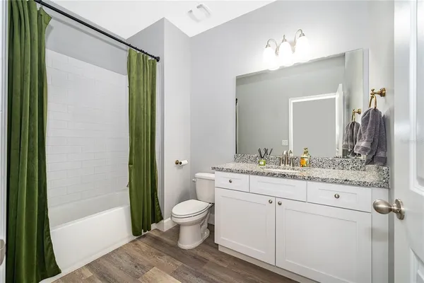 a bathroom with a granite countertop sink a toilet and shower