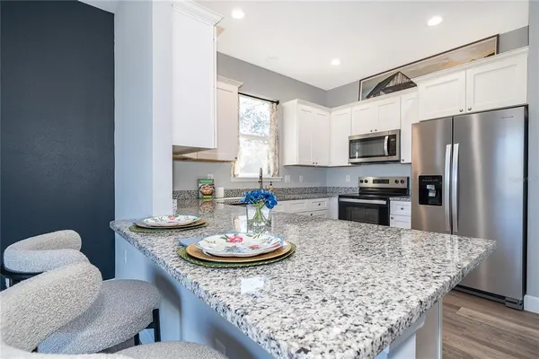 a kitchen with stainless steel appliances granite countertop a table chairs stove and refrigerator