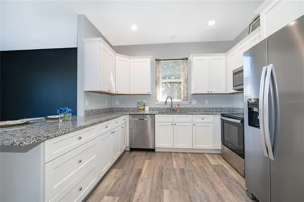 a kitchen with granite countertop cabinets stainless steel appliances a sink and a window