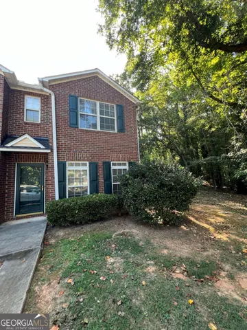 a view of a brick house with a yard and large trees