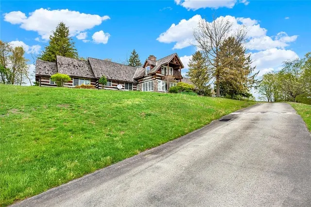 a view of a house with a big yard plants and large trees