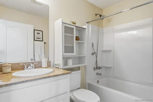 a bathroom with a granite countertop sink toilet and shower