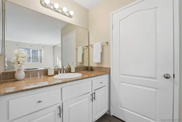 a bathroom with a granite countertop sink and a mirror