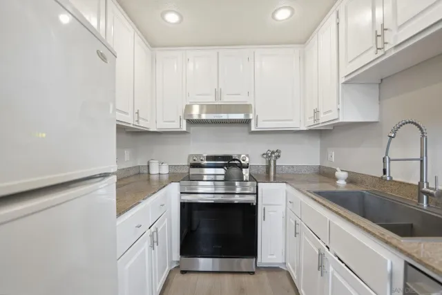 a kitchen with granite countertop white cabinets and stainless steel appliances