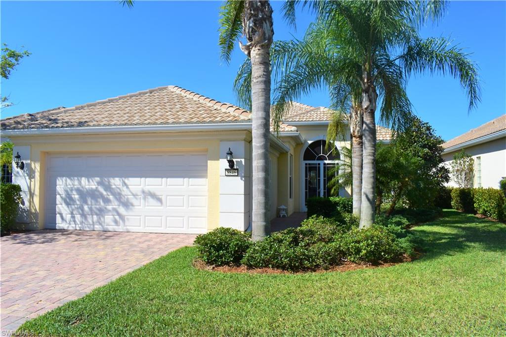 Inviting entry with paver brick driveway and mature landscaping.