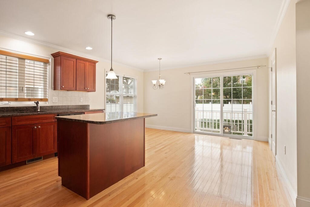 22 School Street, Unit 1 Waltham, MA 02452 - Photo 3 of 12 a kitchen with granite countertop a sink cabinets and wooden floor