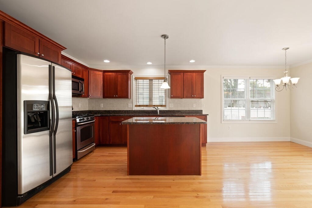 22 School Street, Unit 1 Waltham, MA 02452 - Photo 4 of 12 a kitchen with stainless steel appliances granite countertop a refrigerator a sink dishwasher a stove with wooden cabinets and floor