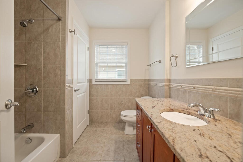 22 School Street, Unit 1 Waltham, MA 02452 - Photo 8 of 12 a bathroom with a granite countertop sink a toilet and shower