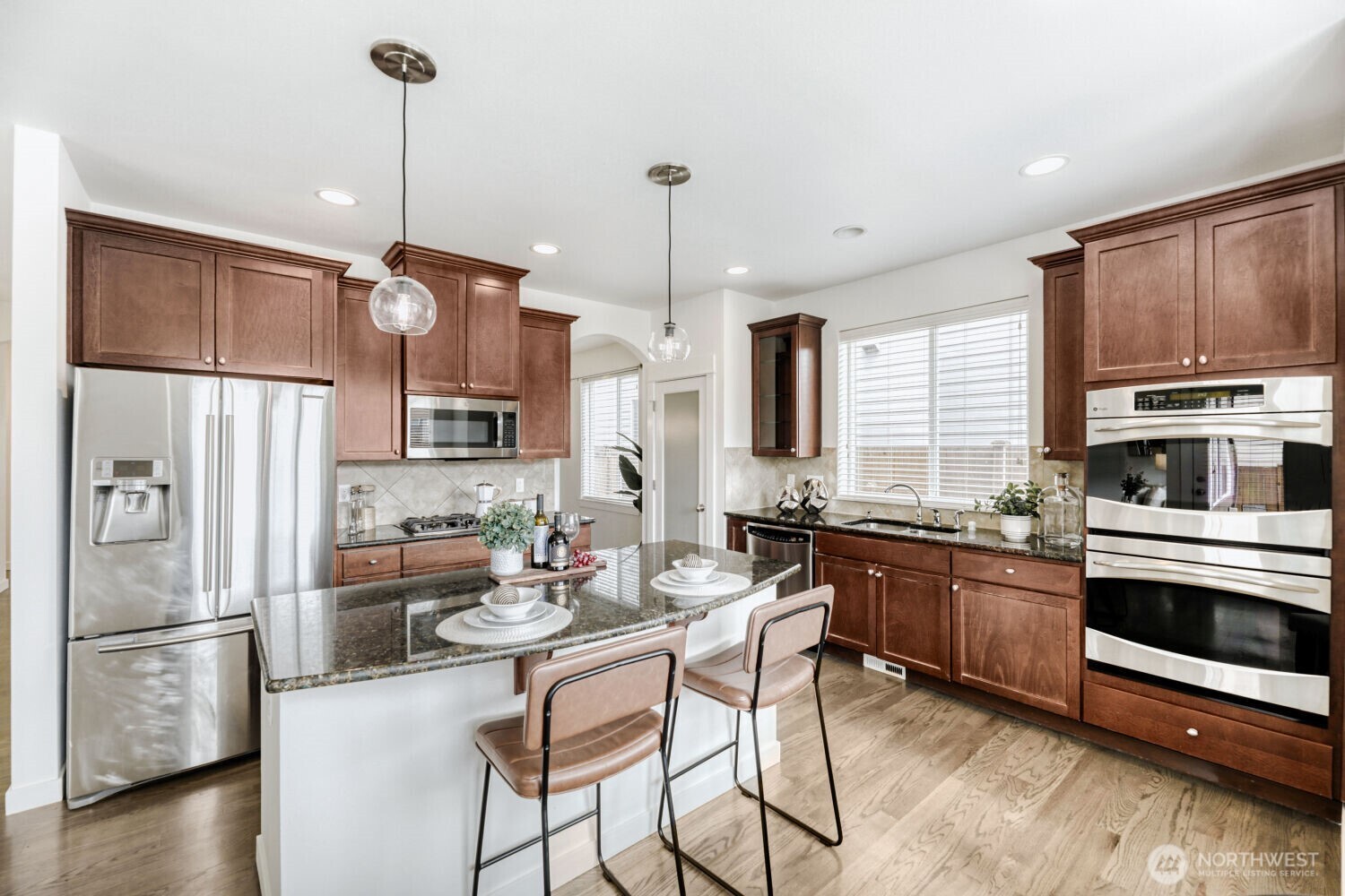 3626 222nd Place Southeast Bothell, WA 98021 - Photo 8 of 27 a kitchen with stainless steel appliances a stove a sink a refrigerator a center island and a wooden floor