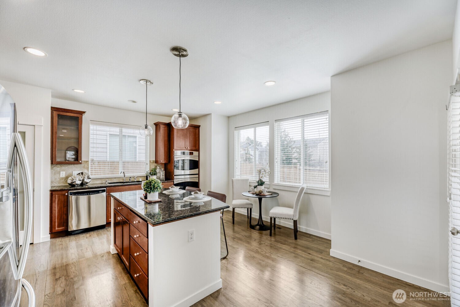 3626 222nd Place Southeast Bothell, WA 98021 - Photo 10 of 27 a kitchen with stainless steel appliances granite countertop a stove top oven a sink dishwasher a dining table and chairs with wooden floor