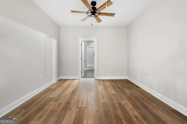 a view of an empty room with window and wooden floor