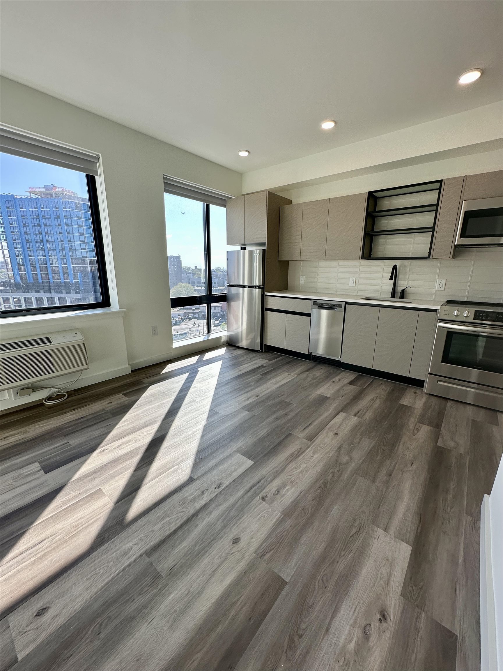 a large white kitchen with stainless steel appliances wooden floors and view living room
