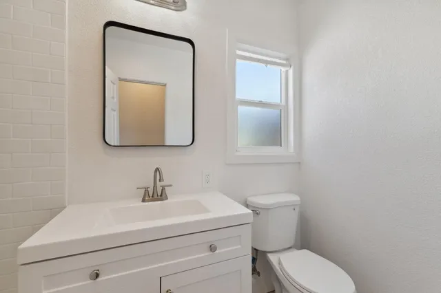 a bathroom with a toilet a sink a vanity and mirror