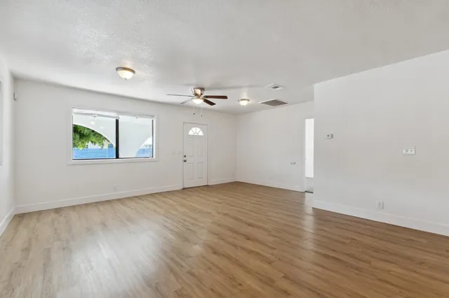 an empty room with wooden floor chandelier and windows