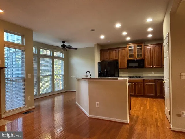 a kitchen with stainless steel appliances granite countertop a refrigerator a sink dishwasher a stove and a large countertops with wooden floor