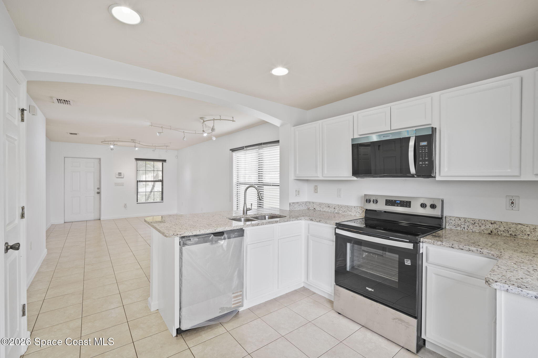 4555 Radiant Way, Unit 103 Melbourne, FL 32901 - Photo 17 of 58 a kitchen with stainless steel appliances granite countertop a sink and a stove top oven with white countertops