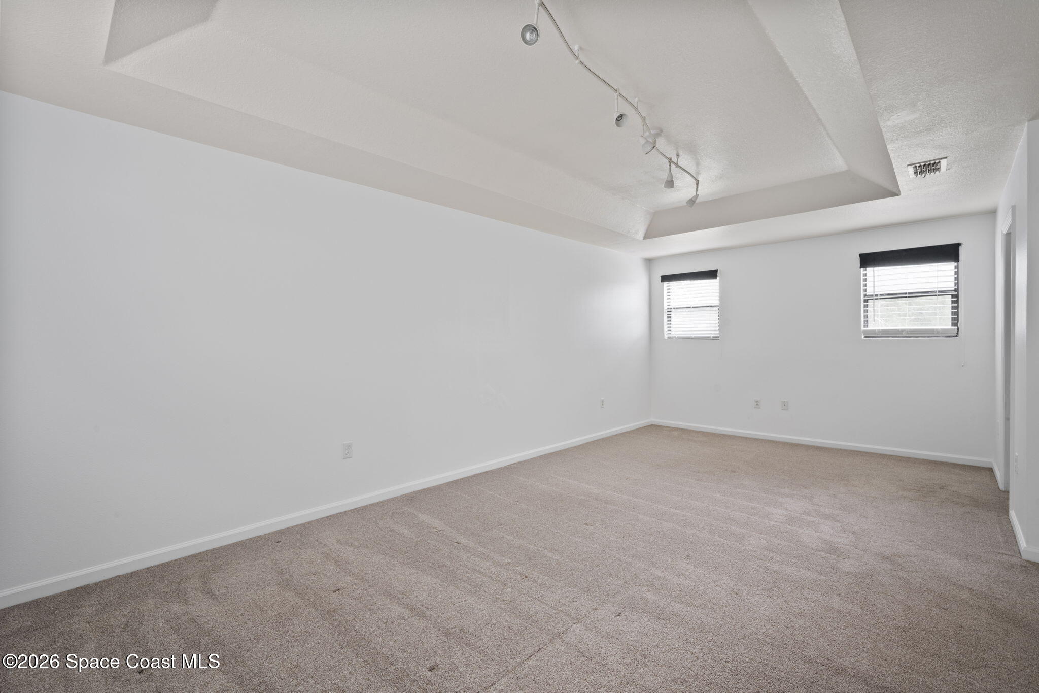 4555 Radiant Way, Unit 103 Melbourne, FL 32901 - Photo 33 of 58 an empty room with a windows and chandelier fan