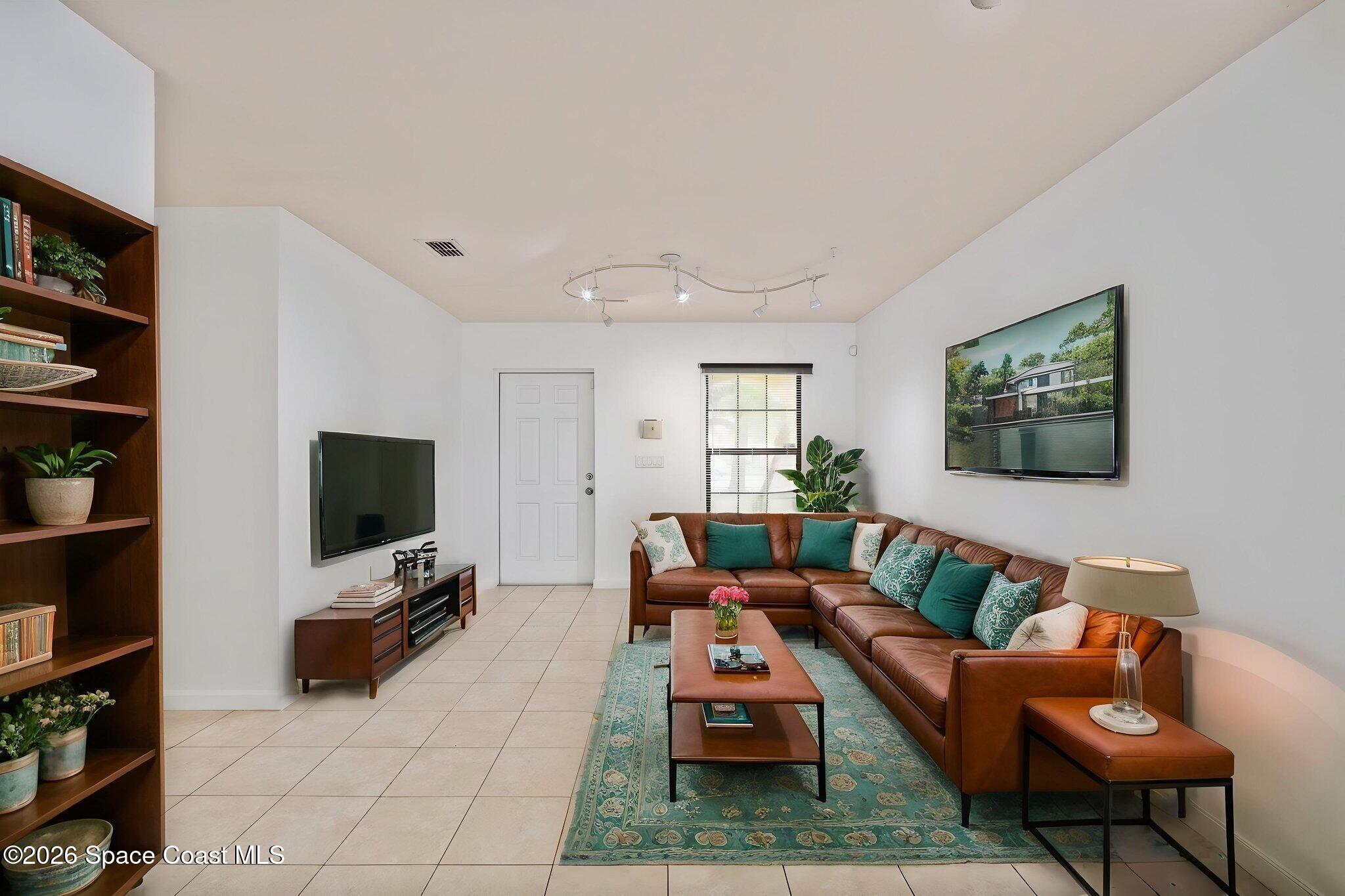 4555 Radiant Way, Unit 103 Melbourne, FL 32901 - Photo 10 of 58 a living room with furniture a flat screen tv and a bookshelf