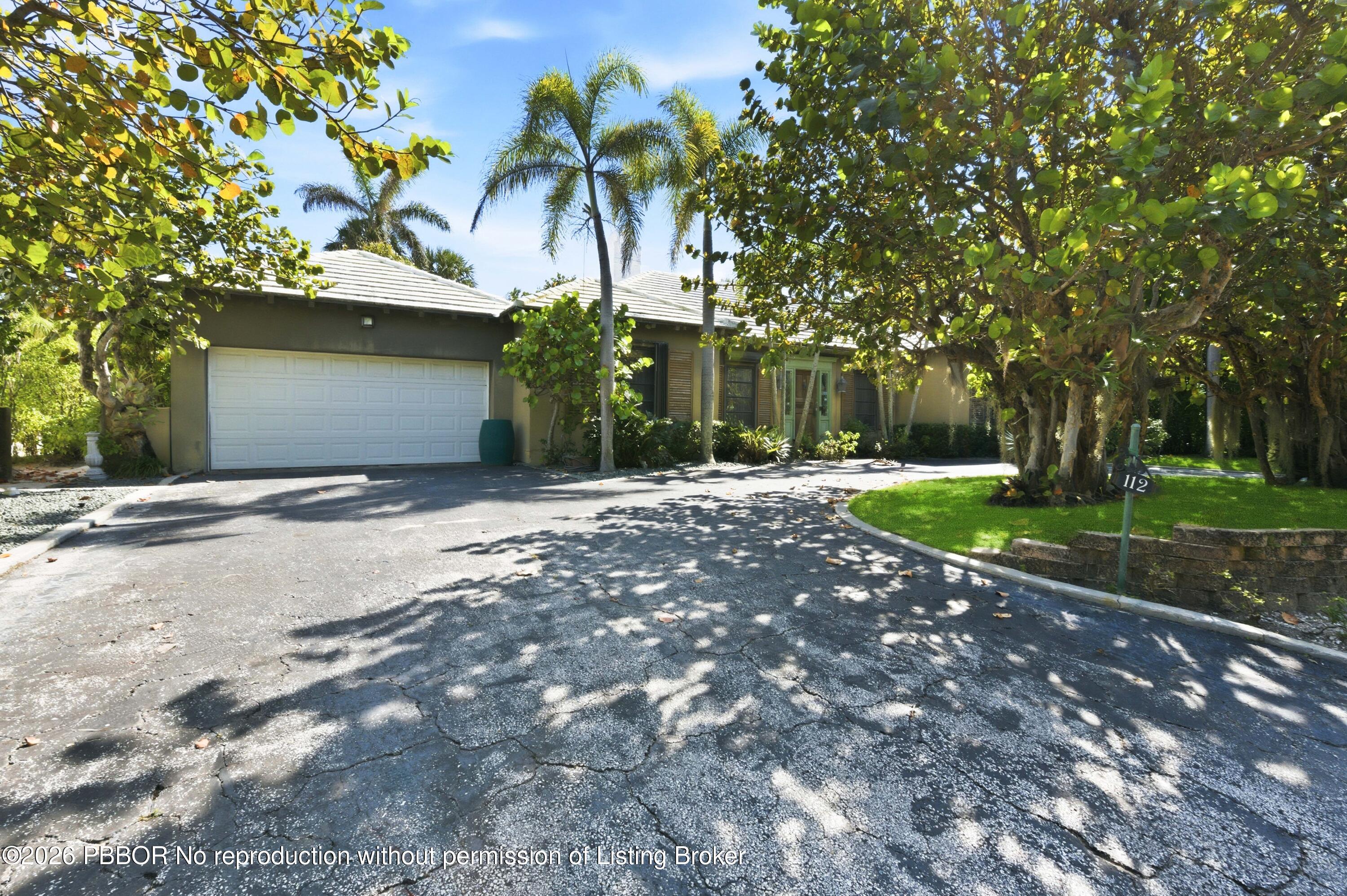 112 Algoma Road Palm Beach, FL 33480 - Photo 2 of 4 a front view of a house with a yard and palm trees