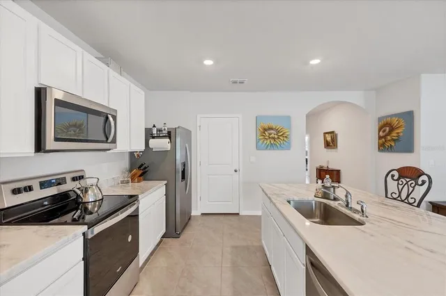 a kitchen with stainless steel appliances a stove a sink a refrigerator a microwave a counter top space and cabinets