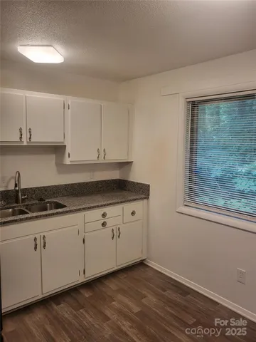 a kitchen with granite countertop white cabinets and sink