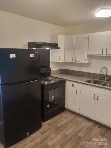 a kitchen with granite countertop white cabinets and black appliances