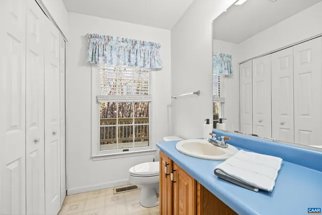 a bathroom with a granite countertop sink a toilet and a mirror