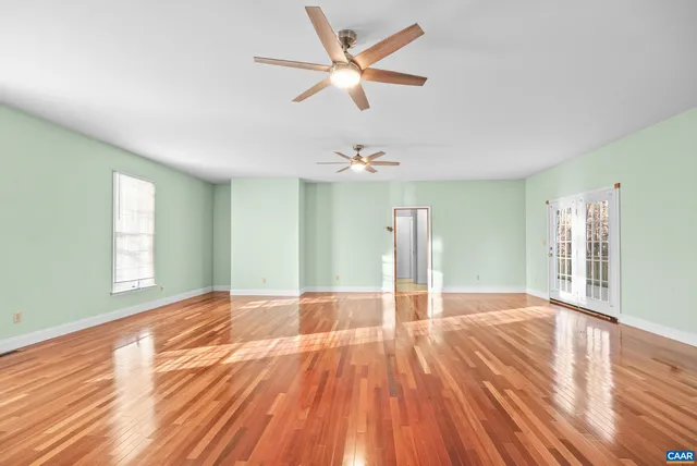 an empty room with chandelier fan and windows