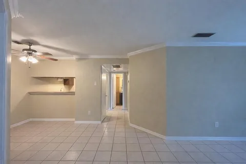 an empty room with windows and ceiling fan