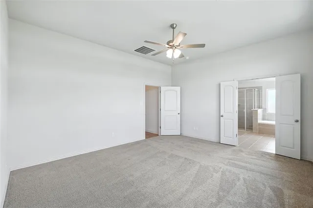 an empty room with a bathroom and a fan