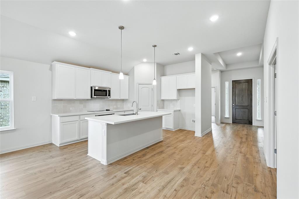 3704 Pitchfork Terrace Anna, TX 75409 - Photo 3 of 31 a large kitchen with cabinets wooden floor and stainless steel appliances