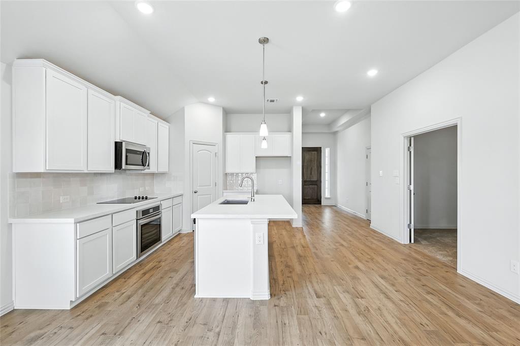 3704 Pitchfork Terrace Anna, TX 75409 - Photo 4 of 31 a kitchen with stainless steel appliances a white stove top oven a sink dishwasher and a refrigerator with wooden floor