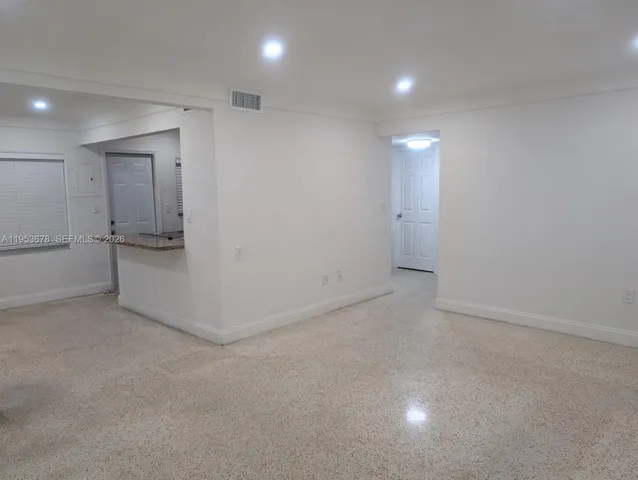 an empty room with white cabinet and a refrigerator