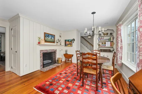 a dining room with furniture a fireplace and wooden floor