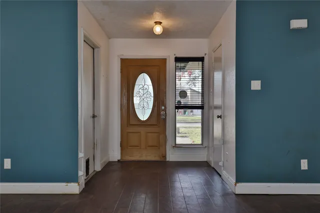 an empty room with wooden floor mirror and windows