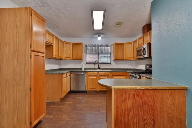 a kitchen with kitchen island granite countertop wooden cabinets a sink and dishwasher