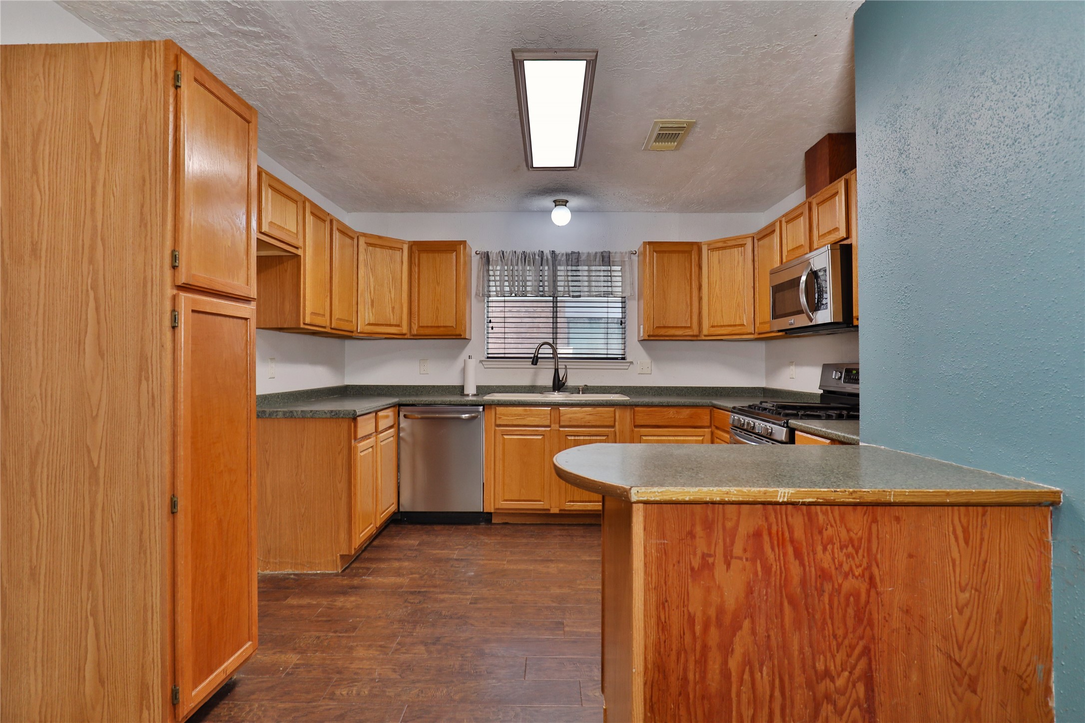 3 Ranch House Loop Angleton, TX 77515 - Photo 9 of 25 a kitchen with kitchen island granite countertop wooden cabinets a sink and dishwasher