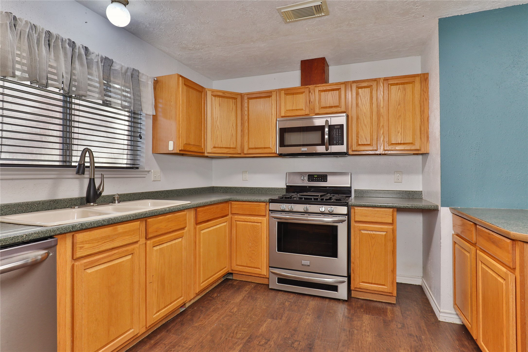 3 Ranch House Loop Angleton, TX 77515 - Photo 10 of 25 a kitchen with stainless steel appliances a stove sink microwave and cabinets