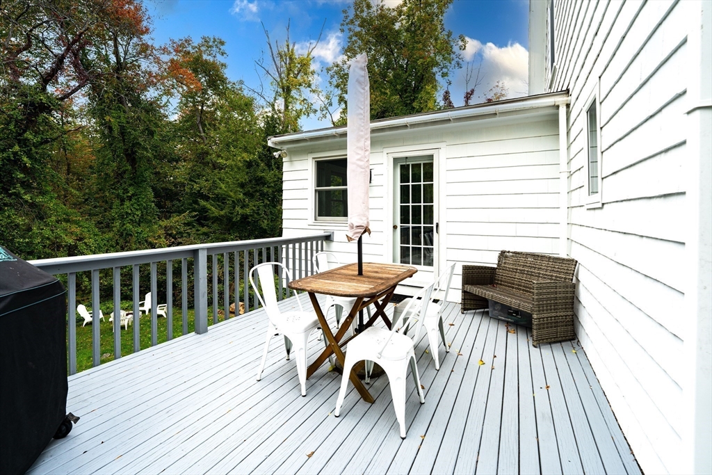 90 Main Street Acton, MA 01720 - Photo 29 of 38 a view of a roof deck with table and chairs with wooden floor and fence