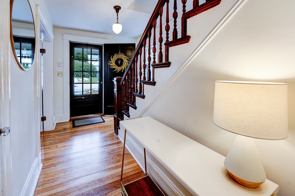 90 Main Street Acton, MA 01720 - Photo 4 of 38 a hallway with wooden floor stairs and a chandelier