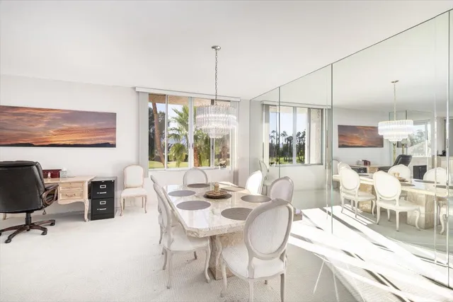 a dining room with furniture a chandelier and kitchen view