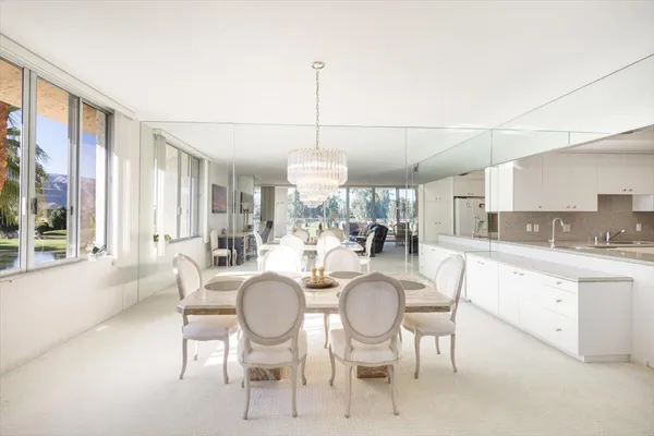 a view of a dining room with furniture a chandelier and large windows