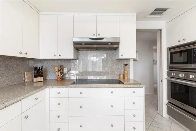 a kitchen with granite countertop white cabinets white appliances and a sink