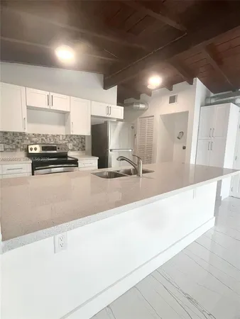 a large kitchen with kitchen island granite countertop a sink and cabinets
