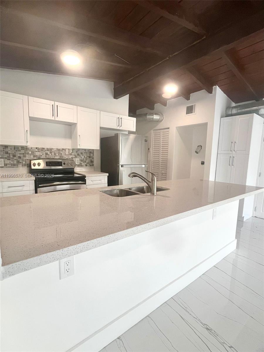 1776 Northeast 178th Street Miami, FL 33162 - Photo 4 of 18 a large kitchen with kitchen island granite countertop a sink and cabinets