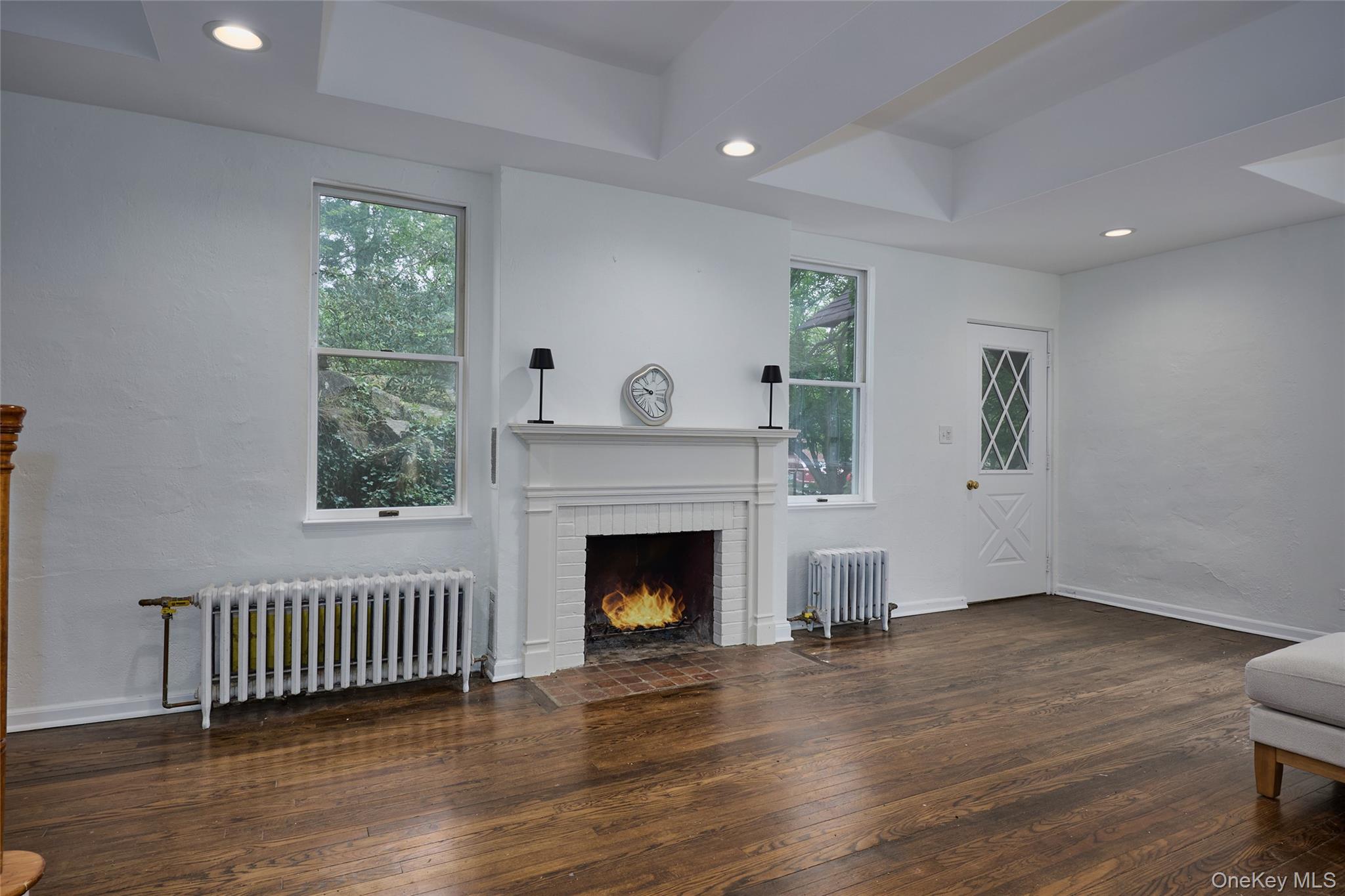 93 Circuit Road Tuxedo Park, NY 10987 - Photo 4 of 34 Unfurnished living room featuring radiator, dark wood finished floors, recessed lighting, and a tray ceiling