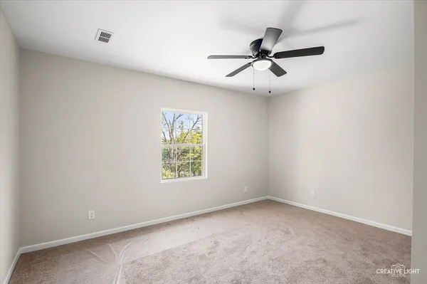 an empty room with windows and fan